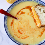 slice of bread dunking into yellow lentil soup