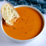 bowl of roasted tomato soup with fresh tomatoes